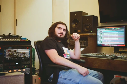 Rami sitting beside the equipment rack and mixing desk in his Toronto studio.